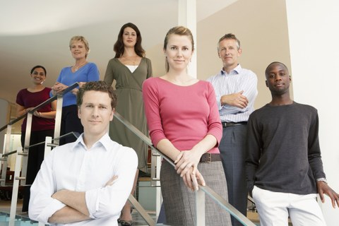 Gruppenfoto von Büroangestellten auf einer Treppe in einem Büro. 