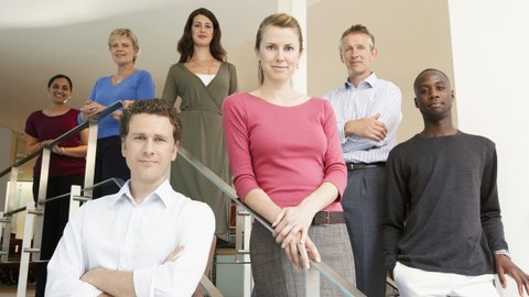 Gruppenfoto von Büroangestellten auf einer Treppe in einem Büro. 