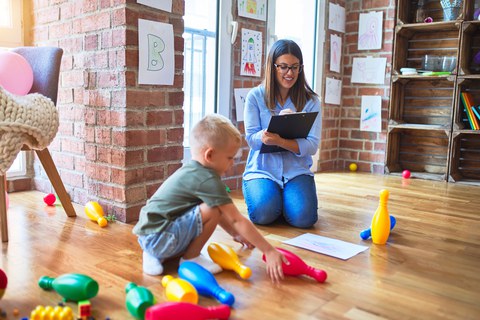 Young therapist woman speaking with child, counselor and behaviour correction at the office around toys