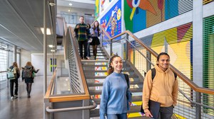 Photo of four students at the TUD chatting as they walk down a flight of stairs.