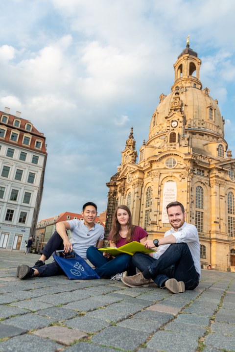 Studierende sitzen auf dem Neumarkt mit der Frauenkirche im Hintergrund