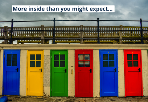 Colorful doors on the beach above sky in autumn  with slogan: More inside than you might expect!