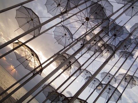Kunstinstallation durchsichtiger Regenschirme vor Meer