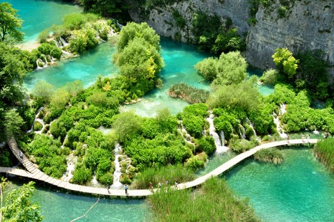 Landschaft mit türkisblauem Wasser, Bäumen und Wasserfällen