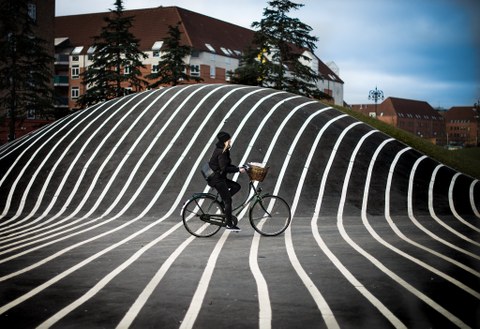 Frau auf Fahrrad vor künstlerisch gestalteter Straße 
