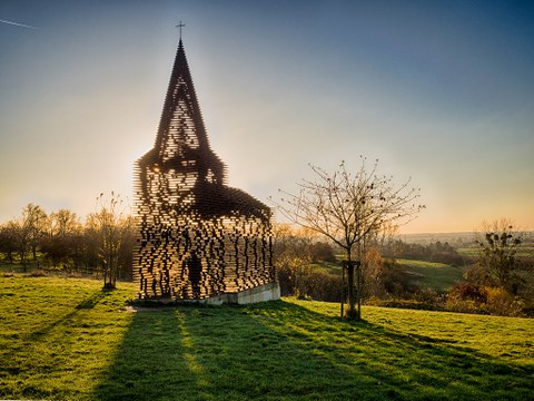 sculpture in the shape of a church, with sunlight shining through the walls