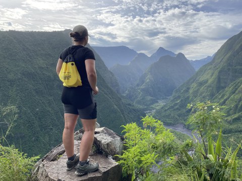 Eine TUD-Studierende an einem Aussichtspunkt über eine grüne Berglandschaft