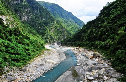 Ein leuchtend blauer Fluss, der sich durch bewaldete Berge schlängelt.