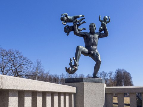 Statue of a man fighting babies that stick to his hands and leg.