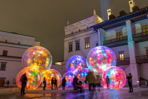 people looking at an art installation made of brightly coloured spheres