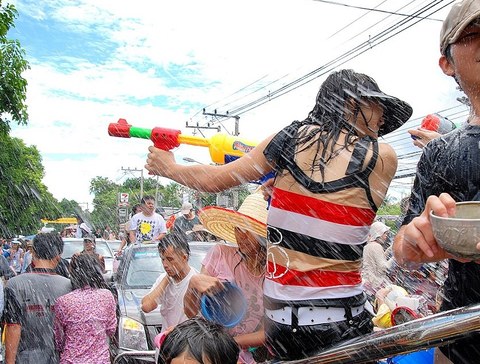 Frau mit Wasserpistole in Menschenmenge, sie duckt sich vor sprühendem Wasser
