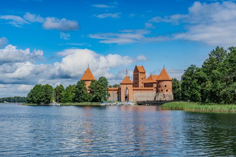 Castle with red roof tiles on a green island in a lake