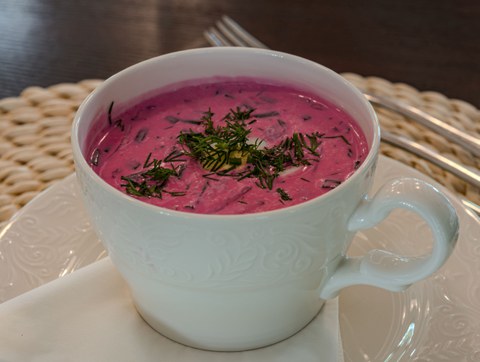 A cup of pink soup topped with a boiled egg and herbs