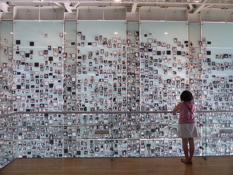 Eine Person steht vor einer Wand voller Portraitfotos