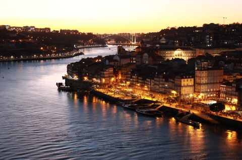 Ansicht einer beleuchteten Stadt am Fluss im Abendlicht
