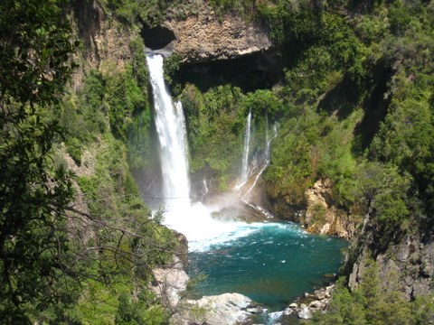 Ein hoher Wasserfall fällt aus einer Felsfront in ein Becken