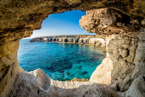 Blick durch einen Höhleneingang auf klares blaues Meer und Felsen