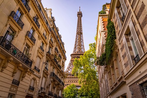 The Eiffel Tower as seen from between the houses of a Paris street.