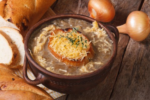 Eine Schüssel mit Zwiebelsuppe, in der auch Käse und Brot schwimmen.