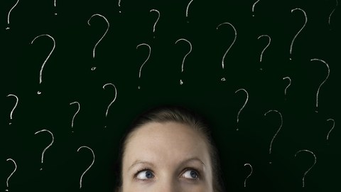 The image shows a photo. In the lower part of the photo you can see the upper half of a face. The eyes are looking to the right. The face is in front of a dark wall. There are many question marks on it.