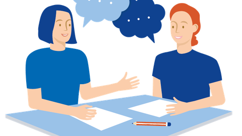 Zwei Personen sitzen sich an einer Tischecke gegenüber und sprechen miteinander. Vor ihnen liegen zwei Blatt Papier und ein Stift.