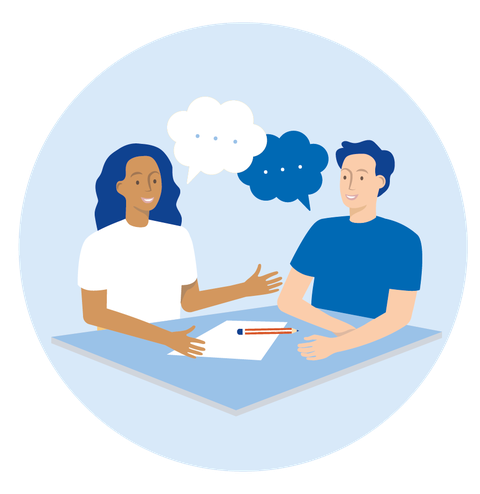 Zwei Personen sitzen sich an einer Tischecke gegenüber und sprechen miteinander. Vor ihnen liegen ein Blatt Papier und ein Stift.