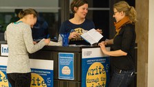 Zwei junge Frauenstehen am Informationstresen und lassen sich zur Langen Nacht des Schreibens beraten.