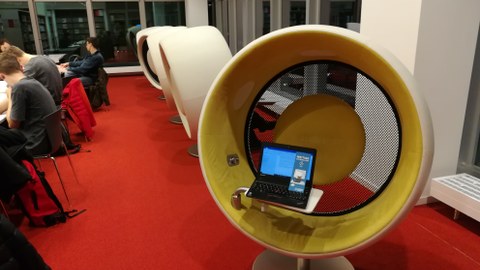 Arbeitsplätze in der Zentralbibliothek Dresden im Kulturpalast, in einem Audiochair steht ein Laptop mit einem Flyer des SZD.