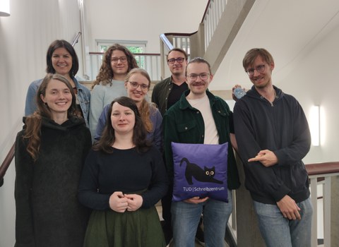 Employees of the writing center are standing on a staircase, all smiling at the camera.