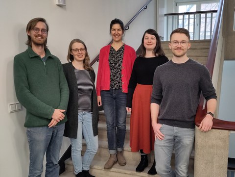 Five employees of the writing center are standing on a staircase, all smiling at the camera.