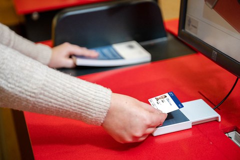 Eine Person hält eine Campuscard an ein Kartenlesegerät der SLUB.