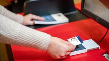 Eine Person hält eine Campuscard an ein Kartenlesegerät der SLUB.