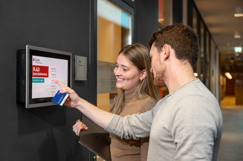 Zwei Personen mit Campuscard stehen an einem Arbeitsraum der SLUB.