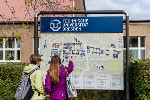 Das Foto zeigt eine Informationstafel. Auf dieser ist die Lage der einzelnen Gebäude auf dem Campus der TU Dresden dargestellt. Vor der Tafel stehen zwei Frauen. Eine zeigt mit ihrem Finger auf ein Gebäude auf der Tafel.