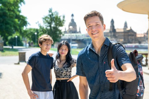 Drei Studenten schauen in die Kamera. Im Hintergrund ist die Dresdner Skyline zu sehen