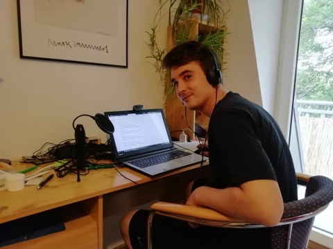 Student sitzt vor seinem Laptop am Schreibtisch zu Hause.