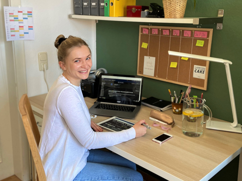 Studentin sitzt zu Hause am Schreibtisch vor ihrem Computer und Tablet.