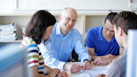 ein Professor im Gespräch mit Studierenden