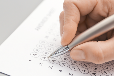 The photo shows a person filling in a questionnaire with a pen. You can only see the person's hand.