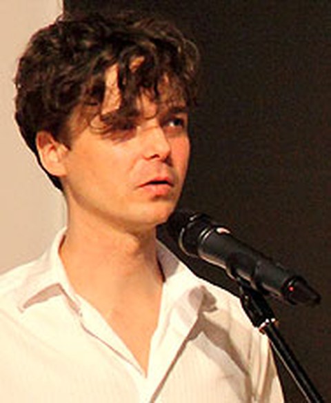 Das Foto zeigt André Eckardt vor einem Mikrofon.