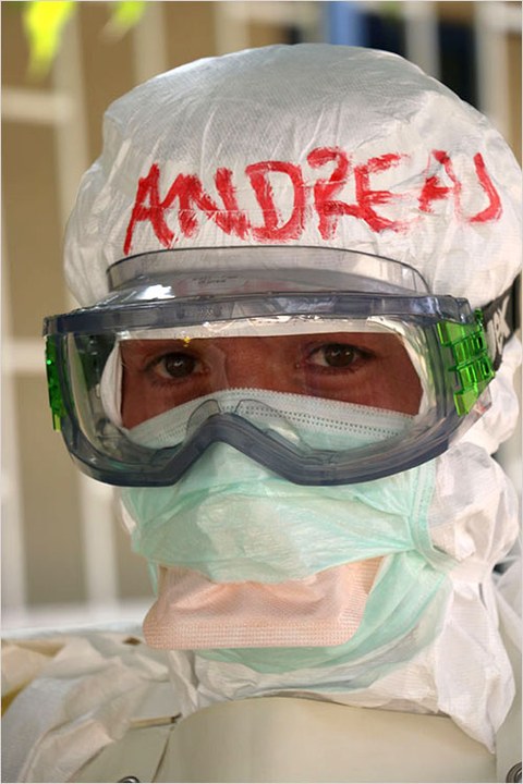 The photo shows Andreas Kurth's head. He is wearing protective gear, complete with a suit, goggles, and several face masks. His name "Andreas" is written in red on his hood.