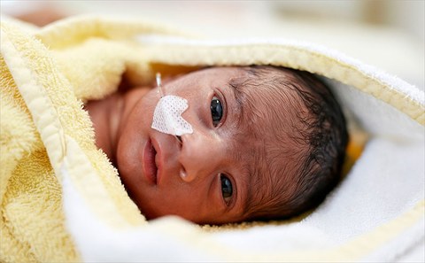 Das Foto zeigt ein Neugeborenes mit einem herzförmigen Pflaster auf der Wange.
