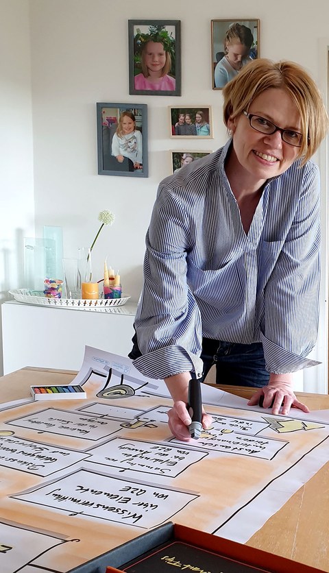 The photo depicts Annikka Zurwehme. She is looking at the viewer and writing on a flip chart with a marker.