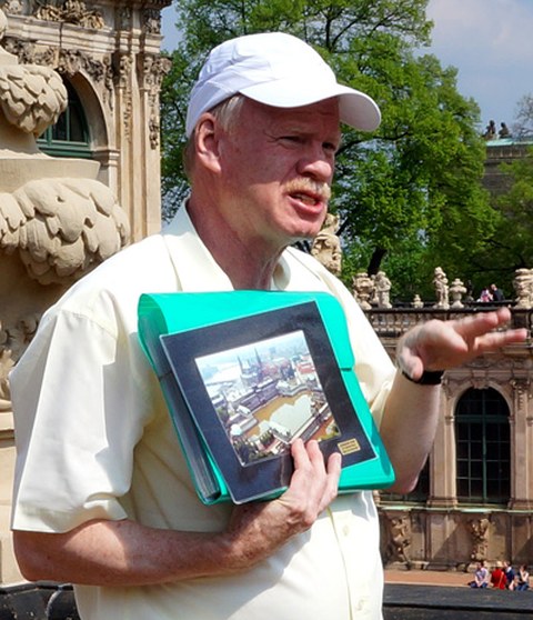 Das Foto zeigt Dr. Günther Kieb. Er hält Fotos in den Händen und erklärt etwas dazu.
