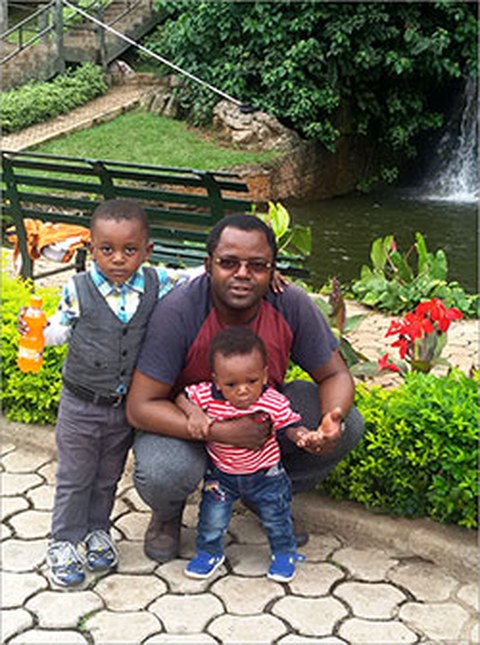 Das Foto zeigt Dr. Sefirin Djiogue mit seinen Kindern vor einem Fluss.