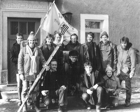 The photo shows a group of young people. They are holding a flag and have gathered for group photo.