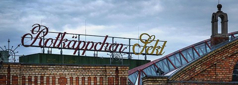 The photo shows a large sign atop a building reading "Rotkäppchen Sekt," which means "Rotkäppchen" sparkling wine.