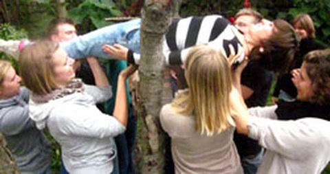 Das Foto zeigt viele Personen, die eine Andere in die Höhe heben. 