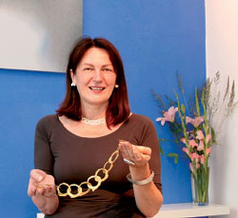 The photo shows Marion Bogda holding a gold chain in her hands.