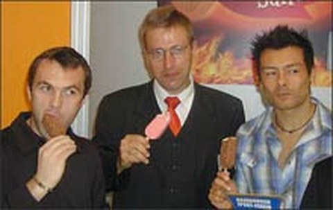 The photo shows three men eating ice cream on a stick.